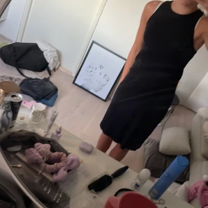 Svart ärmlös kortklänning - Snygg svart kortklänning med ärmlös design och rund halsringning. Klänningen har en tight passform som framhäver figuren och är perfekt för dig som gillar en stilren och enkel look.