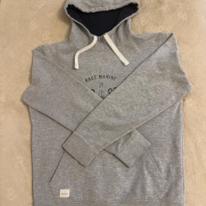 Grå hoodie från Race Marine - Säljer en vintage grå hoodie från Race Marine med marinblått foder i huvan och vit snörning. 