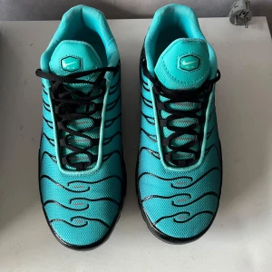 Tn Nike Air Max Plus blå/svarta sneakers priset kan diskuteras - Nike Air Max Plus sneakers i en riktigt fräsch turkosblå färg med svarta detaljer och vågiga linjer. Skorna har svart sula med synliga Air Max-bubblor, vit swoosh på sidan och svarta skosnören. Ovandelen är i mesh för extra andningsförmåga och cool look. Kom privat 