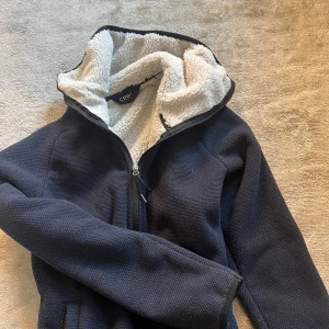 Svart teddyjacka från Crivit med dragkedja - Mysig svart teddyjacka från Crivit som också är i nyskick och använd en gång. NYPRIS 499kr kvitto finns. Storlek S-M men passar XS såklart. Jättefin till stallet men också till att rida ute i kylan vilket är perfekt nu till hösten. Pris kan diskuteras. 