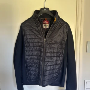 Parajumpers Cardigan  - Tjena! Säljer denna svarta cardigan från Parajumpera då den är förliten. Den är storlek Y-L vilket jag skulle säga är en S eller en liten M. 170-180 skulle jag säga är en perfekt längd för jackan! Den är i superbra skick och har andvänds sparsamt! Tveka inte att höra av dig om du undrar något🤩