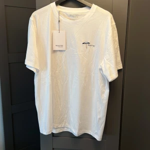 Vit t-shirt från Selected Homme - Säljer en klassisk vit t-shirt från Selected Homme. T-shirten har normal passform, rund halsringning och diskret logga på bröstet. Perfekt basplagg för garderoben.