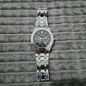 Silver klocka  - Stol klocka i silver med länkarmband och svart urtavla. Klockan har flera små urtavlor och markerade skruvar på boetten. Perfekt accessoar för dig som gillar en klassisk och modern look.