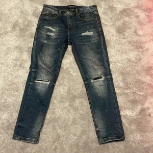 Blå jeans från Supply & Demand - Snygga blå jeans från Supply & Demand med slitna detaljer och dragkedja. Perfekt för en avslappnad stil. Midjan är låg och passformen är tight. Passar perfekt till den som är 170-176. W28 L30