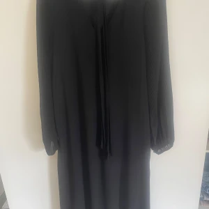 Svart långärmad klänning från Vero Moda - Säljer en svart klänning från Vero Moda i storlek XS. Klänningen har långa, plisserade ärmar och en rak passform. Materialet känns lätt och elegant, perfekt för dig som gillar stilrena plagg med diskreta detaljer.