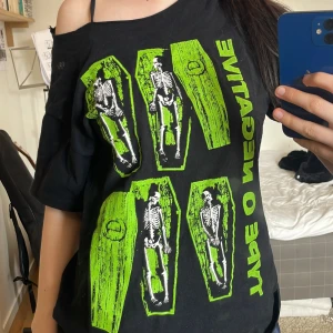 Svart band-tshirt med Type O Negative tryck - Cool svart t-shirt med grönt och vitt Type O Negative tryck framtill. Motivet visar skelett i kistor och texten går vertikalt längs sidan. T-shirten har korta ärmar och en avslappnad passform. ‼️Har gjort den till off shoulder men inga andra ”defekter”‼️