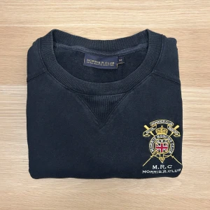 Morris Tröja Navy XS - Säljer en stilren svart tröja från Morris R Club med ett broderat emblem på bröstet. Tröjan har långa ärmar och ribbade muddar vid ärmslut och nederkant. Perfekt för en avslappnad look.