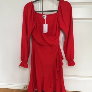 Röd omlottklänning  - Snygg röd omlottklänning från bubbleroom med långa puffärmar och volangdetaljer. Klänningen har djup v-ringning och markerad midja. Perfekt för dig som vill sticka ut med en färgstark look.klänningen är aldrig använd💞