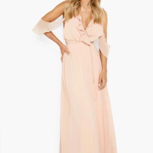 Ljusrosa långklänning med volang och omlott - Säljer en romantisk ljusrosa långklänning med omlott och volangdetaljer. Klänningen har offshoulder-ärmar och ett knytband i midjan som framhäver siluetten. Perfekt för sommarens speciella tillfällen. Har även en slits. Aldrig använt och har prislapp kvar. 