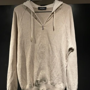 Beige stickad hoodie från Gran Sasso - Lyxig hoodie i bomull/cashmere-blandning från italienska Gran Sasso. Klassisk modell i tidlös beige – perfekt för stilrena dagar. Storlek 48 – passar S/M. Nypris: 4 299kr Plagget är i mycket bra skick. Kan sänka priset vid snabb affär.