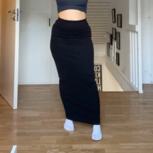 Svart maxi kjol i stretchigt material - Säljer en svart långkjol med tight passform från Gina Tricot. Kjolen är enkel och stilren utan synliga detaljer och har en rak siluett. Perfekt för dig som gillar minimalistisk stil och vill ha en kjol som sitter snyggt och bekvämt. Är för lång för mej som är 160, ifall jag inte har den lika högmidjat på bilden. Så den är ganska lång. 