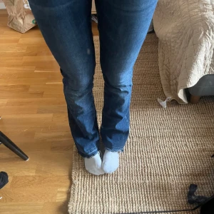 Mörkblå jeans från Hunkydory - Säljer ett par mörkblå jeans från Hunkydory med raka ben och råa, fransiga benslut. Jeansen har klassisk femficksdesign, silverfärgade knappar och kontrastsömmar. Perfekta för en avslappnad och stilren look.