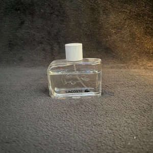 Lacoste Essential herrparfym - Fräsch och sportig parfym från Lacoste i en genomskinlig glasflaska med vit kork. Flaskan har den klassiska krokodilloggan ingraverad och rymmer en lätt citrusdoft. Perfekt för dig som gillar en ren och energisk känsla.