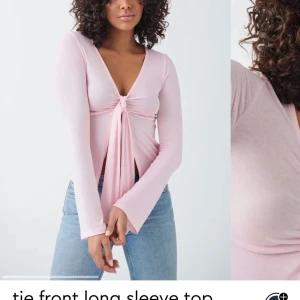 Ljusrosa knytblus med lång ärm - Trendig ljusrosa topp med lång ärm och knyt framtill. Djup v-ringning och mjukt, stretchigt material som sitter snyggt på kroppen. Perfekt att styla med jeans för en cool look.💖             Endast provad men passade inte över bysten