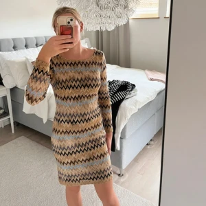Mönstrad klänning från Pernilla Wahlgren - Säljer en snygg långärmad klänning från Pernilla Wahlgren med zigzag-mönster i beige, blått och svart. Klänningen är figurnära och har rund halsringning samt mjukt innerfoder för extra komfort.