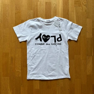 CDG T-shirt - Säljer denna feta t shirt av CDG med sitt klassiska tryck. Den passar bra för dig som vill gå runt med en stilren look på sommaren. Säljer T-shirten så billigt pga att lite av trycket har smält när t shurten skulle strykas, det syns lite grann men den fyller fortfarande sin funktion! Det är bara att höra av sig vid minsta lilla fundering ☺️