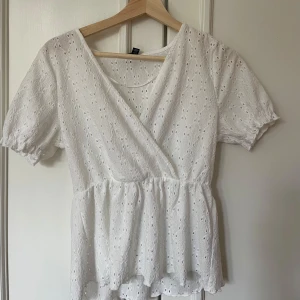 Vit omlottblus med broderade detaljer - Säljer denna söta vita omlottblus med puffärmar. I nyskick och nästan aldrig använd.