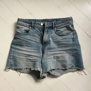 Blå jeansshorts - Snygga blå jeansshorts från H&M x Brock Collection med fransig kant nertill och klassisk femficksdesign. Shortsen har normal passform och är tillverkade i denim med slitna detaljer för en avslappnad look. Har blivit för små så säljer. Skriv för fler bilder💞