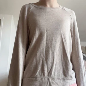 Beige långärmad tröja från Sofie Schnoor - Säljer en enkel och stilren beige långärmad tröja från Sofie Schnoor. Tröjan har rund halsringning och är tillverkad i ett mjukt material som passar perfekt till vardags. Diskret blixtdetalj nertill på sidan.