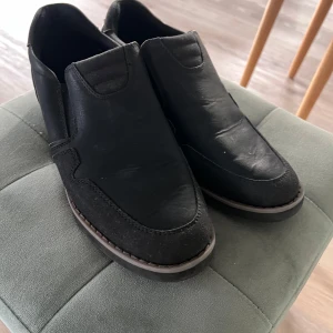 Svarta loafers från Stepside Comfort - Säljer ett par svarta loafers från Stepside Comfort i storlek 40. Skorna har en stilren design med rund tå och platt sula, tillverkade i skinn och syntet. Perfekta för dig som vill ha bekväma och snygga skor till vardags eller fest. Använda fåtal tillfällen. 