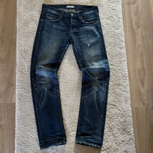 Selvedge jeans från Uniqlo - Säljer ett par selvedge jeans från Uniqlo med raka ben och femficksmodell. Jeansen har en snygg tvätt med slitningar och små färgstänk för en cool, använd look. Passar perfekt till vardags och har normal passform.
