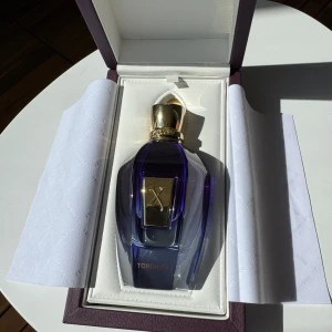 Torino21 Eau de Parfum från Xerjoff (90-95ml) - Lyxig parfymflaska i blått och guld från Xerjoff, modell Torino21. Flaskan har en elegant, facetterad design med guldfärgad etikett och lock. Kommer i exklusiv presentask. Innehåller 90ml ml Eau de Parfum. (Enligt bild)