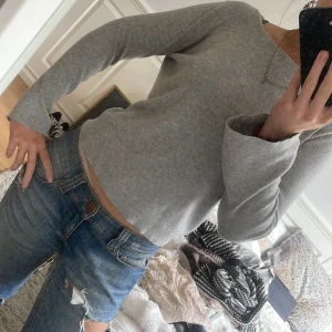 Grå ribbad tröja med snörning i ryggen - Säljer en ljusgrå ribbad tröja med långa ärmar och snygg snörningsdetalj i ryggen. Tröjan har en enkel och stilren design som passar perfekt till jeans eller kjol. Haha vad är detta för ai som skriver texterna men de funka ju iallafall!