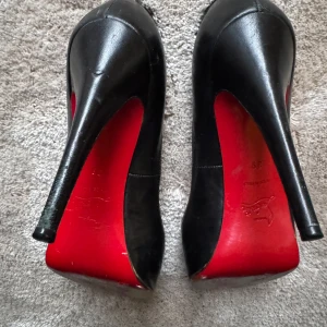 Svarta klackskor från Christian Louboutin strl 39 - Säljer ett par ikoniska svarta pumps från Christian Louboutin, modell Very Prive 120 Kid. Skorna har klassisk röd sula, öppen tå och hög klack. Tillverkade i skinn och passar perfekt för dig som vill sticka ut. Inköpta på Schuterman. Kvitto finns ej. Originalbox medföljer. Skorna har små skavanker här och där. 