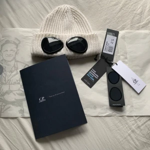  Vit Cp Company mössa  - Vit merino ull mössa från C.P. Company med  goggles. Mössan är i ny skick och köptes för 1599kr självklart äkta!  Allt på bilderna medföljer! Pris kan diskuteras!