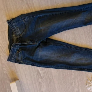  Mörkblå bootcut jeans - Säljer ett par mörkblå jeansbyxor med klassisk femficksdesign och raka ben. Jeansen har normal passform och är tillverkade i denim. Perfekta för en avslappnad stil.