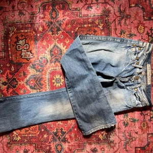 Vintage bootcut jeans - Säljer ett par klassiska blå jeans från Take two med skinn detaljer och guldfärgat broderi på bakfickorna . Jeansen är bootcut och har tydliga slitningar för en cool look.  Måtten tvärs över: midja: 37 cm innerbenslängden: 81 cm benöppningen : 23 cm.     Skriv privat för mer info 💞