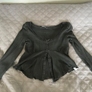 Svart långärmad topp med spets från Gina Tricot - Supersöt svart långärmad topp från Gina Tricot med spetsdetaljer och liten rosett framtill. Är öppen fram till. 