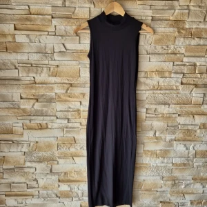 Svart ärmlös midiklänning från Club L - Säljer en svart midiklänning från Club L med hög hals och ärmlös design. Klänningen har en  tight passform som ger en stilren och minimalistisk look. Perfekt för dig som gillar enkla och eleganta plagg.