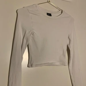 Vit croppad långärmad topp - Säljer en enkel och stilren vit croppad långärmad topp från Gina Tricot. Toppen har rund halsringning och är figurnära i modellen, perfekt att matcha med jeans eller kjol.