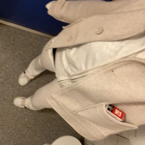 Beige kappa från lager 157 - Säljer en stilren beige kappa från lager 157 med klassisk krage och stora fickor framtill. Jackan har knappar och är långärmad, perfekt för dig som vill ha en enkel men snygg look. Använd 1 gång perfekt schik storlek XS eller 165 passar även på S/M 