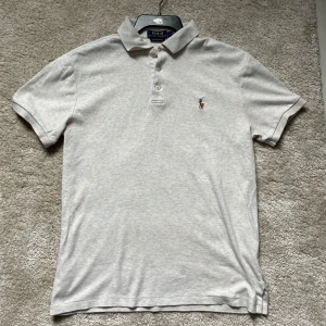Ljusgrå Polo Ralph Lauren Piké - Säljer en ljusgrå piké från Polo Ralph Lauren med klassisk krage och knappar framtill. Pikén är i slimfit passform och är i S. QR kod finns och fungerar. Tar emot prisförslag, kom gärna dm vid frågor!🙂