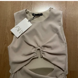 Zara topp beige - Trendig beige topp från Zara med cut-out detalj, ny med prislappen kvar men har fått en liten sminkfläck på insidan när den provades🩷pris är diskuterbart 