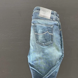 Blå jeansbyxor från Jacob Cohen - Säljer ett par klassiska blå jeans från Jacob Cohen med snygg tvätt och femficksmodell. Byxorna har normal passform och silverfärgade detaljer vid fickorna. Perfekta för dig som gillar stilrena jeans med exklusiv känsla. (Nypris 6000kr) obs håll i höger ficka inuti men går att sy!!
