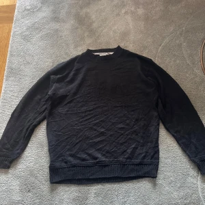 Svart stickad tröja från Lacoste - Klassisk svart stickad tröja från Lacoste. Den har en deskret design på tröjan med laacoste märket. Är i mycket bra skick! Skriv om du undrar något!