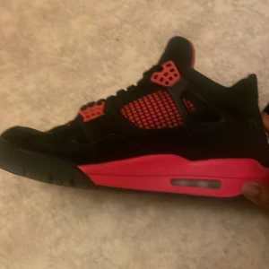 Svarta och röda Nike Air Jordans - Säljer ett par snygga Nike Air Jordans i svart med röda detaljer och vit logga på tungan. Skorna har snörning, platt sula och klassisk siluett. Perfekta för dig som vill sticka ut med en ikonisk sneaker.