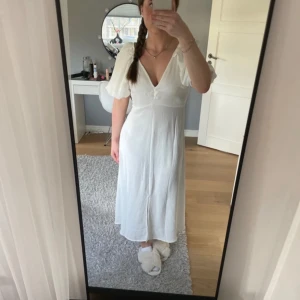 Vit klänning från Neo Noir - Säljer en vit klänning från Neo Noir med v-ringning och kort puffärm. Klänningen har en figurnära passform upptill och faller sedan rakt ned. Perfekt till studenten, skolavslutningar, midsommar och liknande. Klänningen är aldrig använd och prislapp finns kvar. 😊🌸