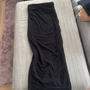 Svart långkjol  - Säljer en svart långkjol. Kjolen har en rak och elegant passform som faller snyggt längs kroppen. Perfekt att styla med en enkel topp eller stickad tröja.