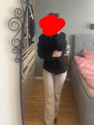 Svart dubbelknäppt rock - Stilren svart rock med dubbelknäppning och krage. Modellen är figursydd och har en klassisk design som passar perfekt till höst och vår  Rocken har fickor på sidorna och är tillverkad i ett mjukt tyg som ger en snygg siluett.