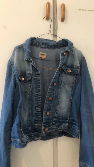 Blå jeansjacka från ONLY - Snygg blå jeansjacka från ONLY med klassisk krage, bröstfickor med knapp och slitna detaljer. Jackan har kopparfärgade knappar och en croppad passform. Skriv om du vill se den på, pris kan diskuteras ❤️