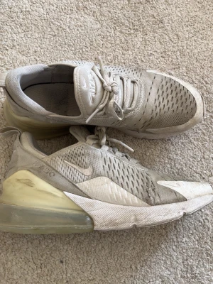 Nike Air Max 270 beige sneakers - Säljer ett par Nike Air Max 270 sneakers i beige med vit sula och genomskinlig Air Max-häl. Skorna luften på vänster häl har gått ut lite men skorna fungerar fortfarande utmärkt