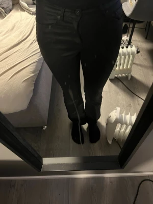 Svarta  jeans - Säljer ett par svarta jeans med rak passform och lågmidjad midja. Jeansen har knapp- och dragkedjestängning samt fickor fram och bak. Perfekta för en stilren och enkel look. Dom svänger ut där nere. 