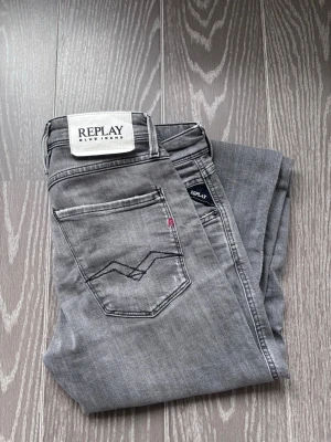 Grå slitna jeans från Replay - Säljer ett par grå jeans från Replay med slitningar på knäna och smal passform. Jeansen är i storlek 29/30 och är knappast använda. Hör av er vid frågor. 