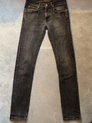 Svarta jeans från Lee - Säljer ett par svarta jeans från Lee med klassisk femficksdesign och dragkedjegylf. Jeansen har en lätt tvättad look och smal passform som sitter tajt längs benen. Perfekta för en stilren och modern outfit.