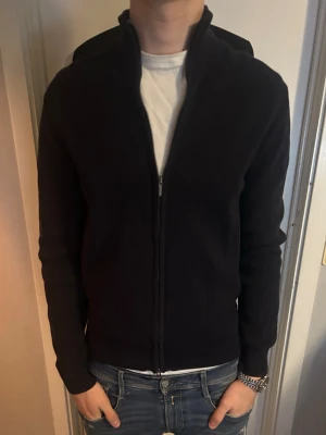 Svart ziptröja med hög krage - En stilren marinblå tröja med dragkedja och hög krage. Går att matcha med en skjorta eller tshirt under. Märket är bläck, strlk M, köpt för 900kr. Pris kan diskuteras.
