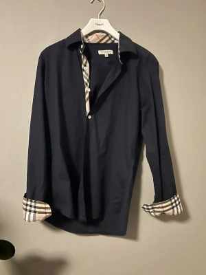 Burberry skjorta mörkblå L (passar M) – mycket fint skick - Säljer en stilren mörkblå skjorta från Burberry.  Storlek: L men sitter mer som en M Skick: mycket bra  Klassisk modell i hög kvalitet. Perfekt till både vardag och mer uppklätt.  Finns i Göteborg. Kan skickas.